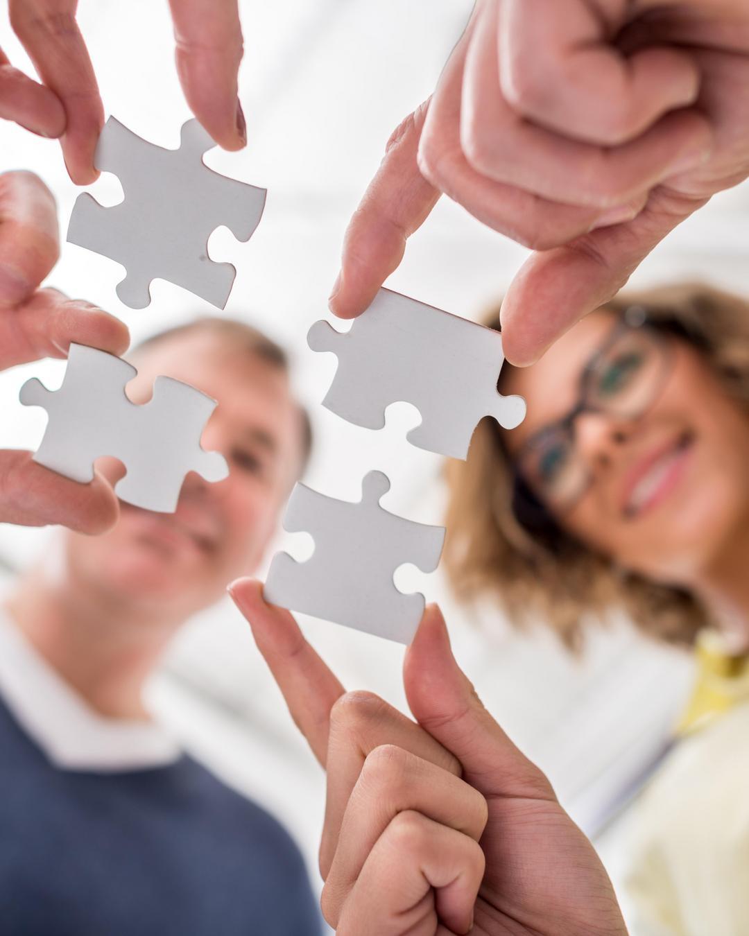 Two people fit four puzzle pieces together