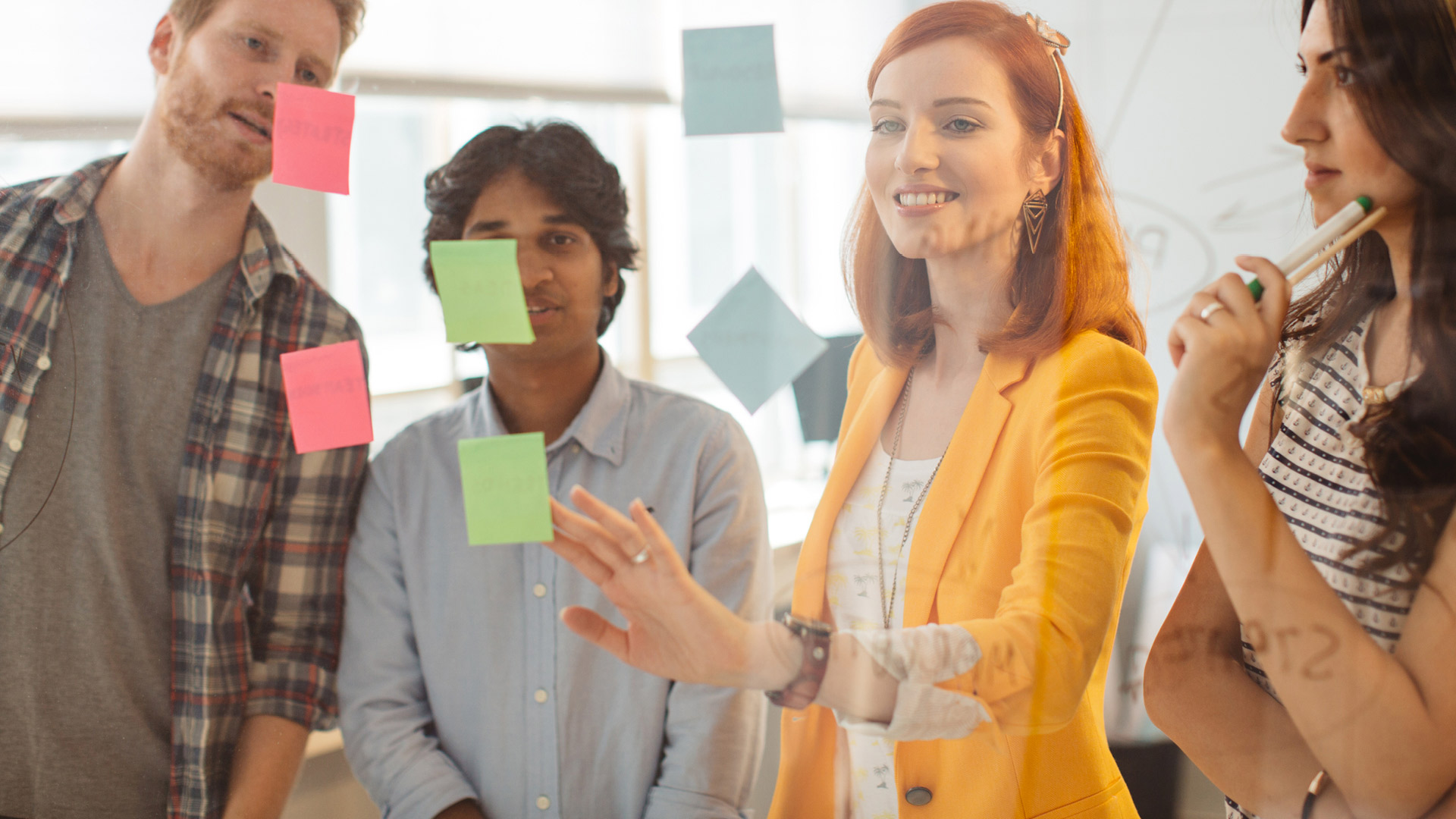Eine Frau, die neben einem Mann steht, mit Post-it-Zetteln an einer Glaswand