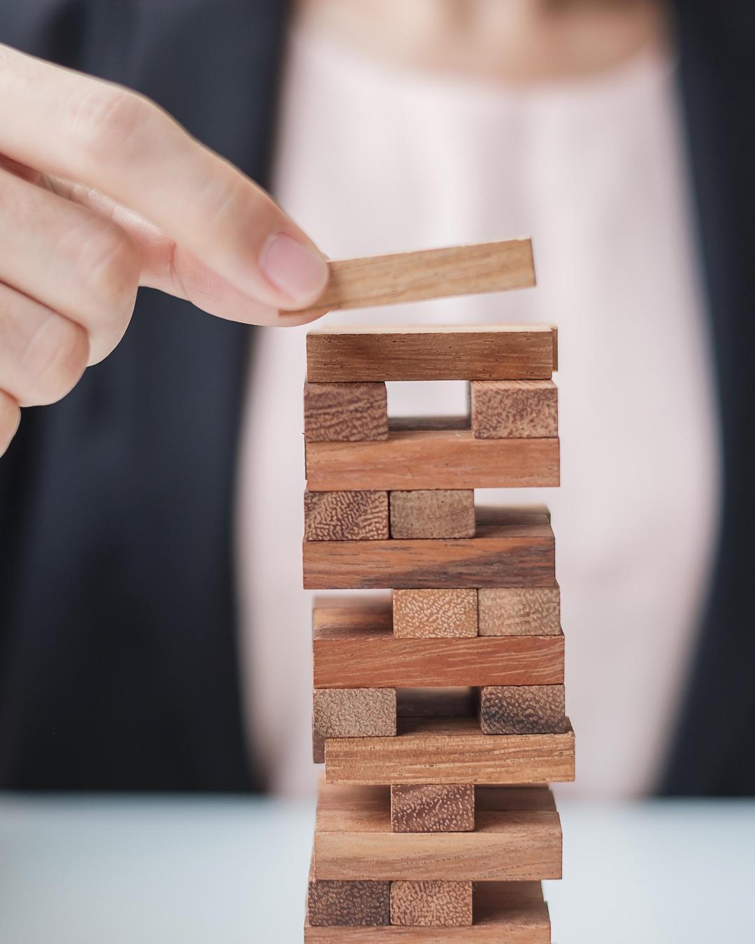 A woman is building a tower out of wooden blocks