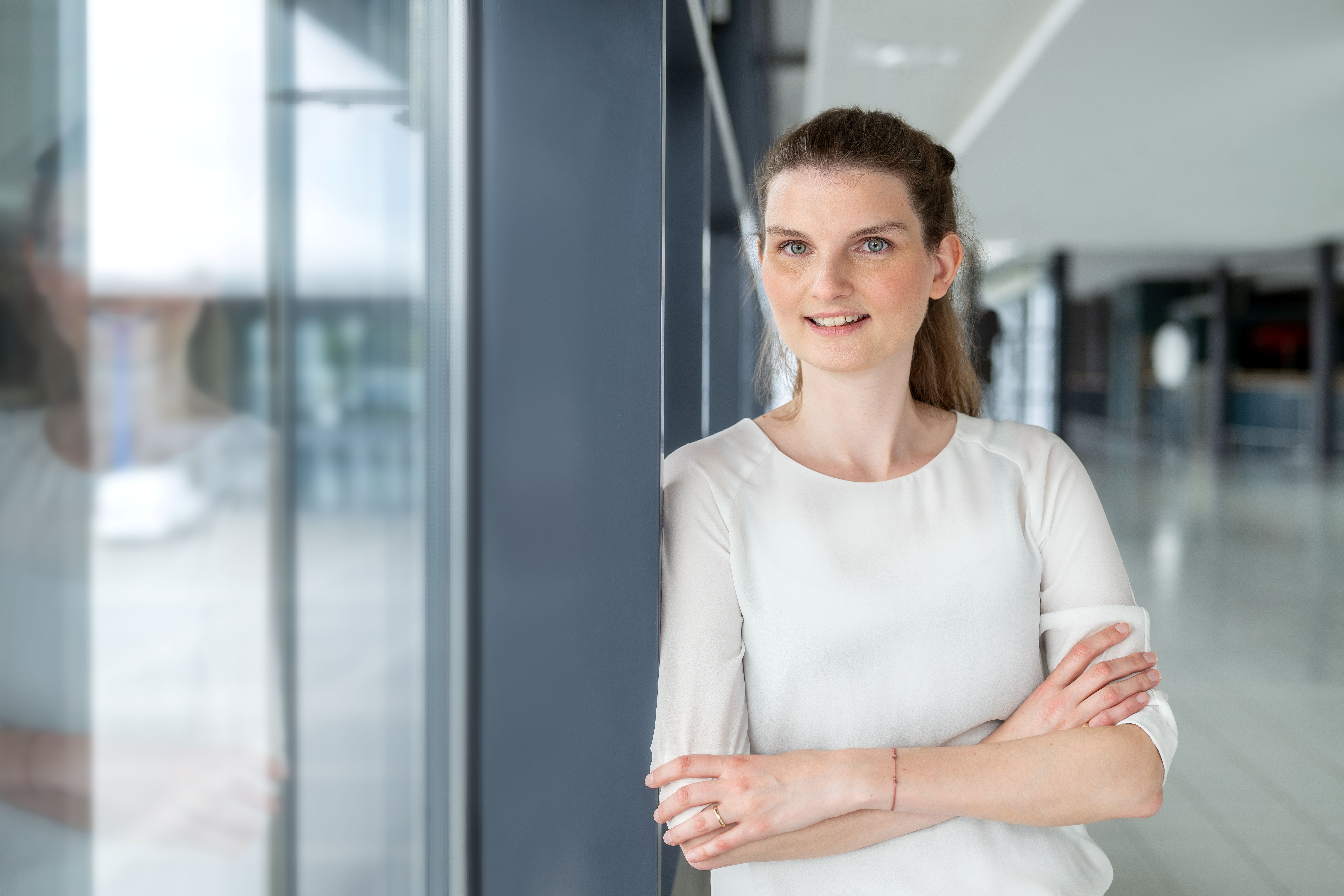 A woman is crossing her arms and is smiling into the camera.
