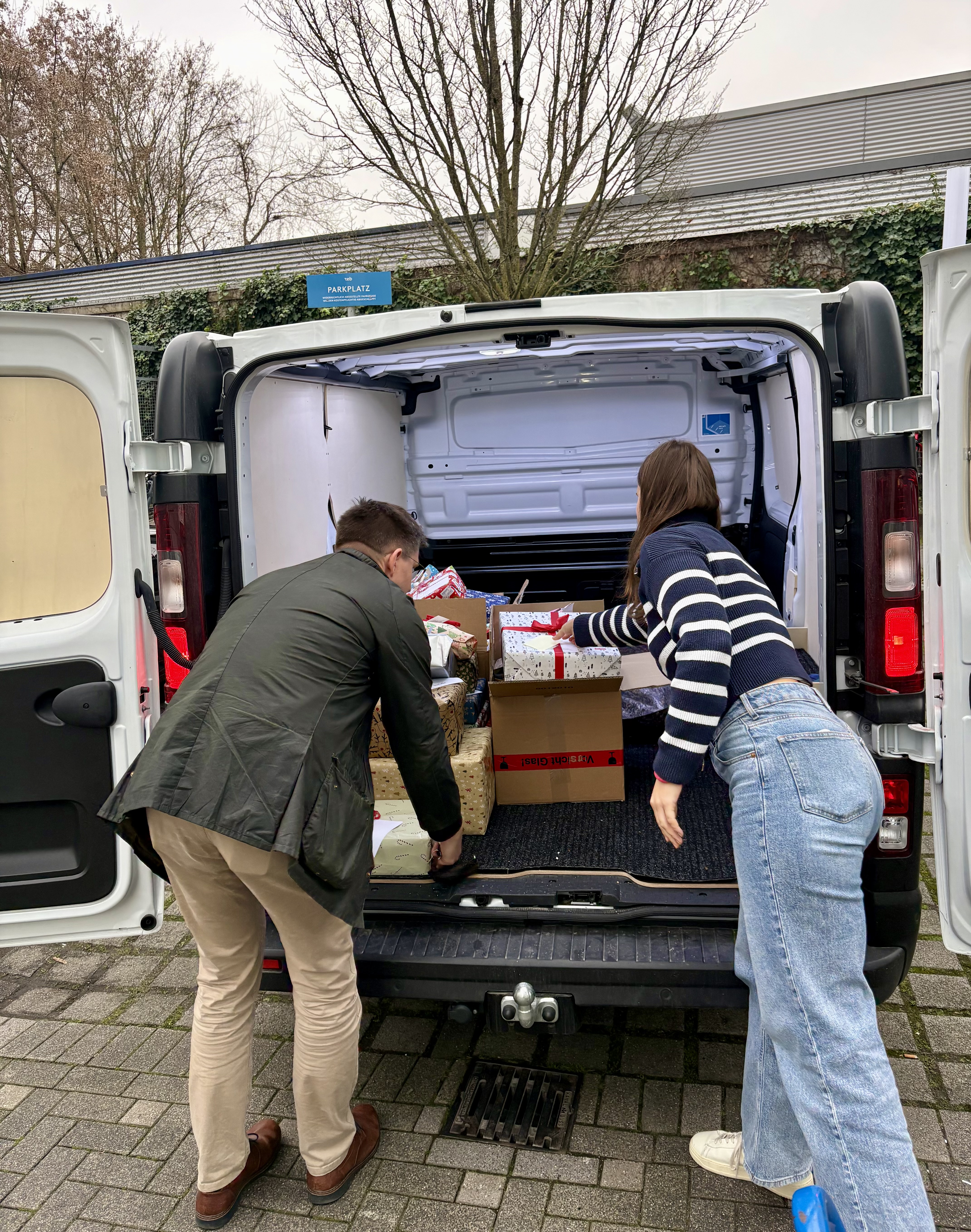 Ein Mann und eine Frau laden Geschenke in ein Auto ein.