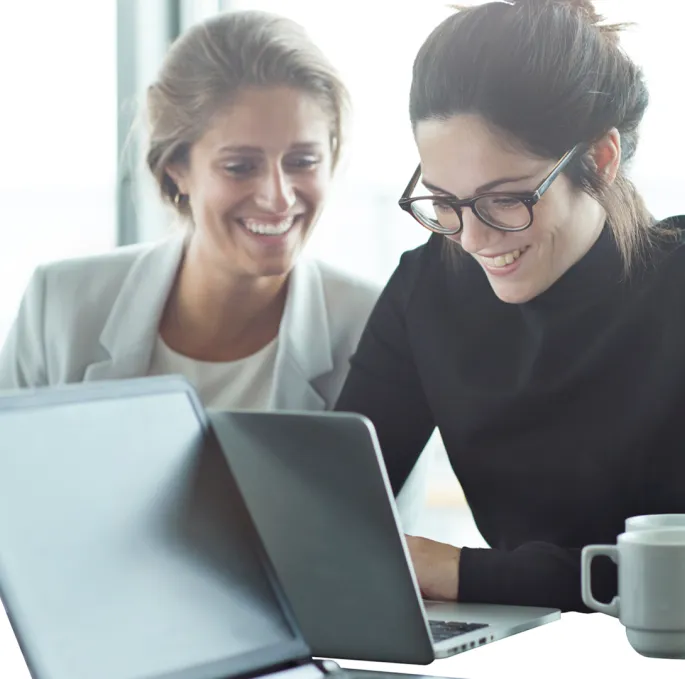 a couple of women looking at a laptop
