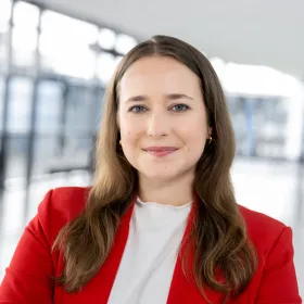 Eine Frau in einem Blazer lächelt in die Kamera.