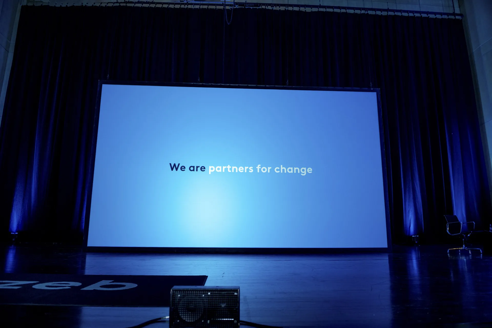Bildschirm auf einer Bühne mit den Worten "Partners for change"
