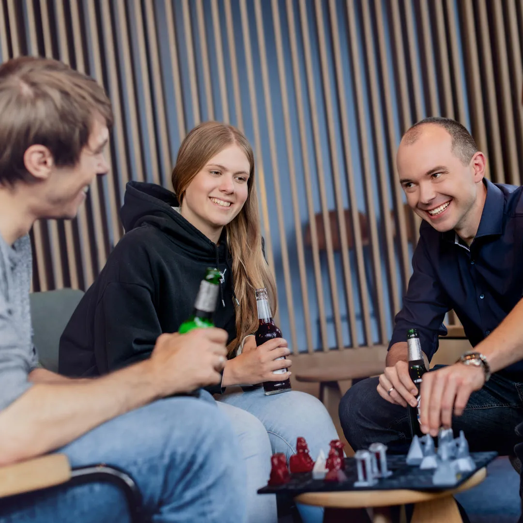 Mitarbeitende der Softwareentwicklung sitzen zusammen und trinken ein Bier.