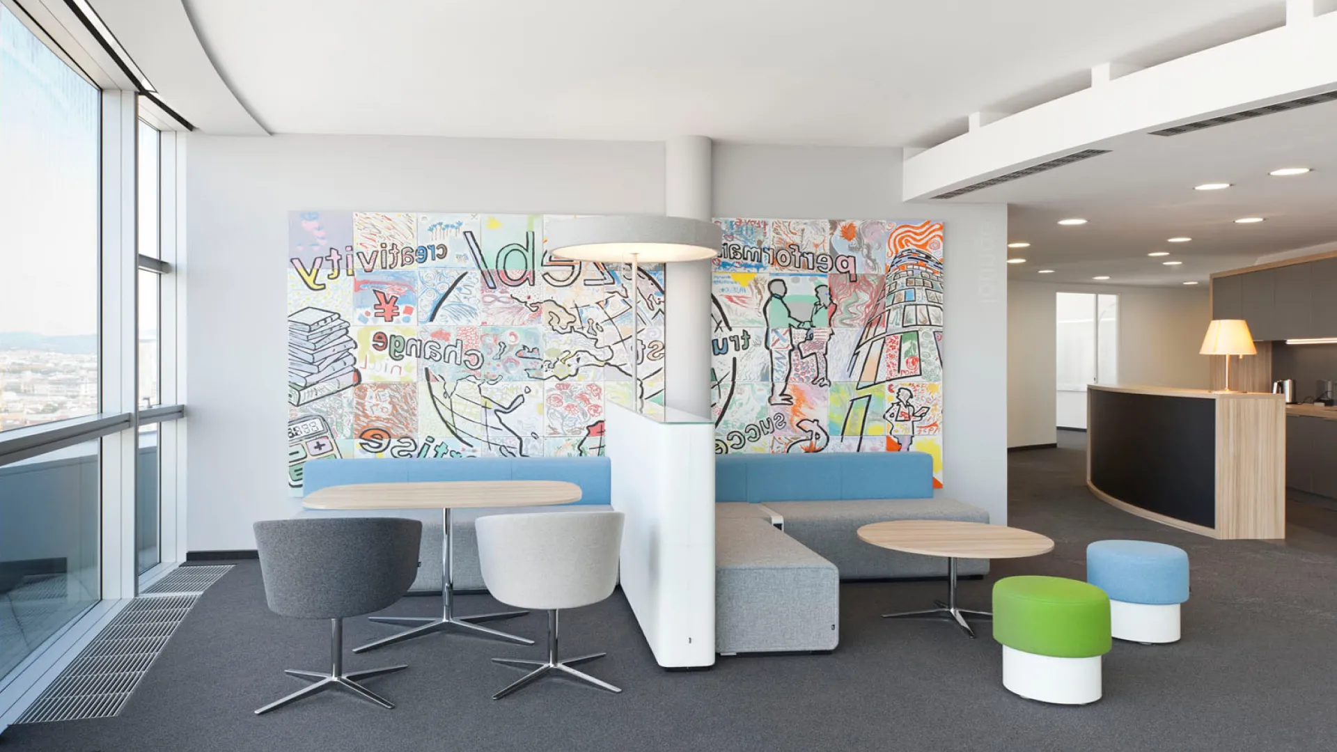 Ein Bild des Büros in Wien. Im Vordergrund sind einige Sitzmöglichkeiten, im Hintergrund ein großes Bild in bunten Farben zu sehen.