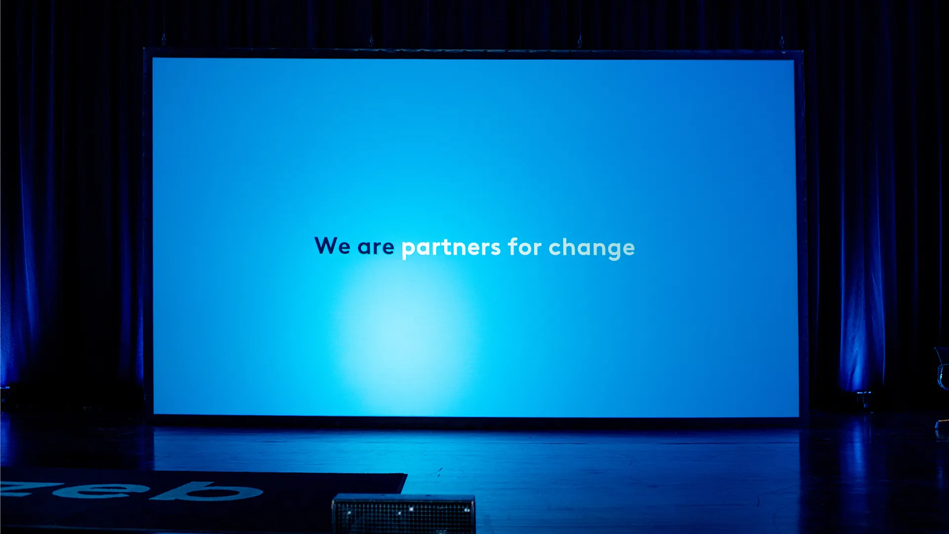 Auf einer Leinwand ist der zeb-Slogan "Partners for change" zu sehen.