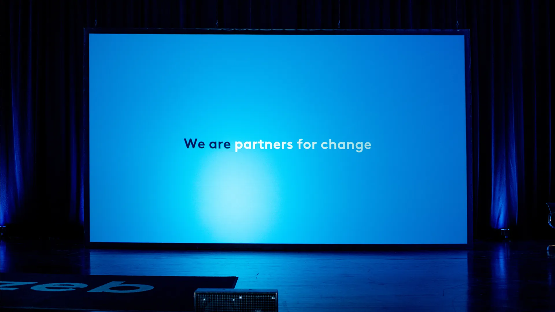 Auf einer Leinwand ist der zeb-Slogan "Partners for change" zu sehen.