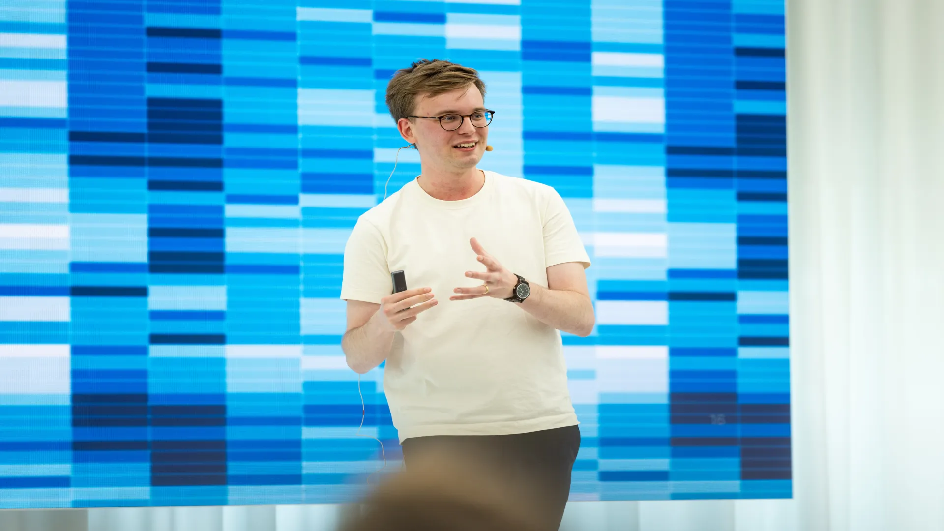 A speaker with glasses and a white sweater