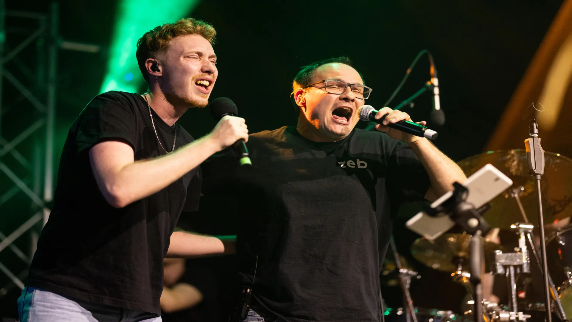 two men singing into microphones on a stage