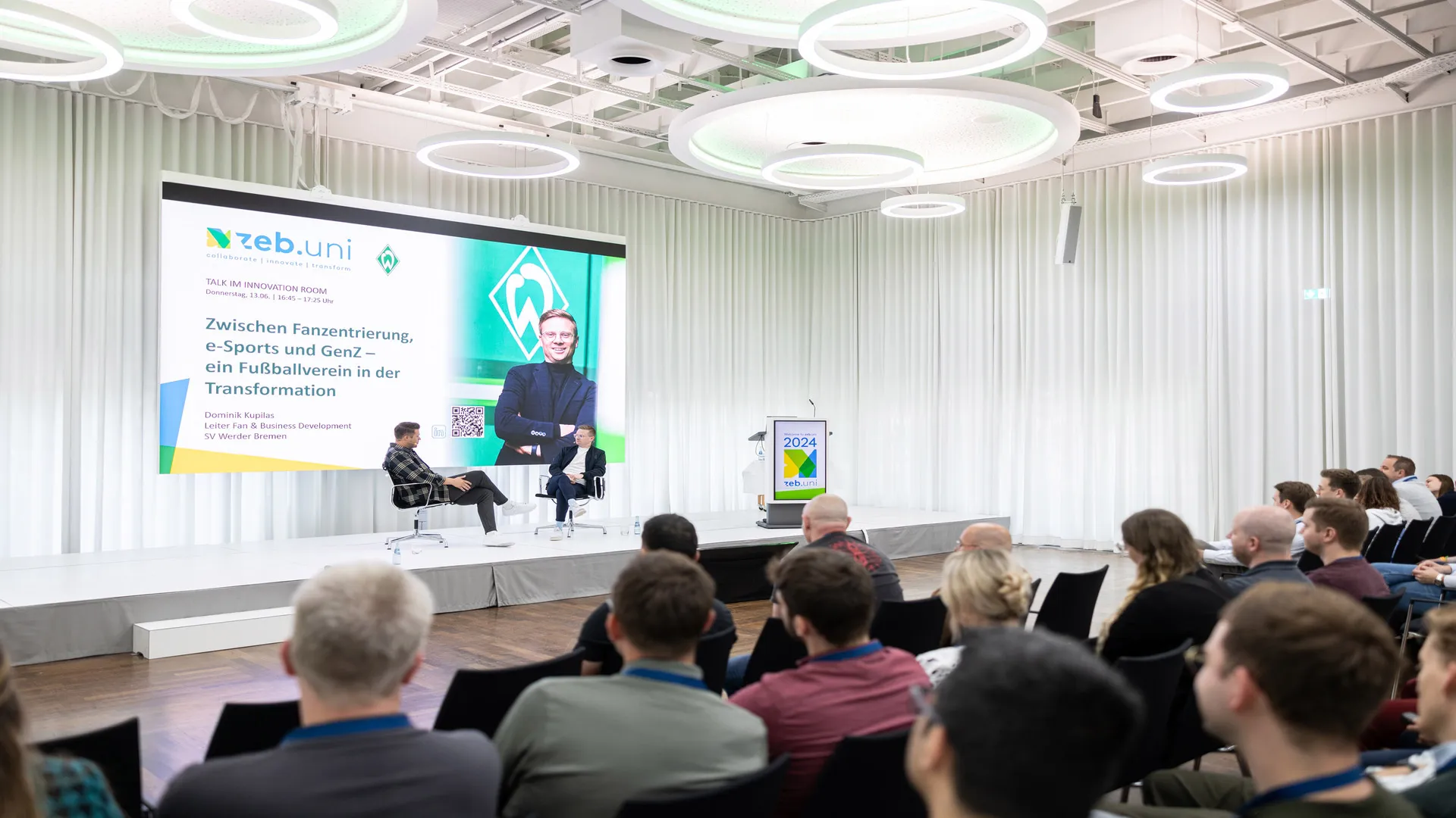 A discussion panel on stage, with the audience in front