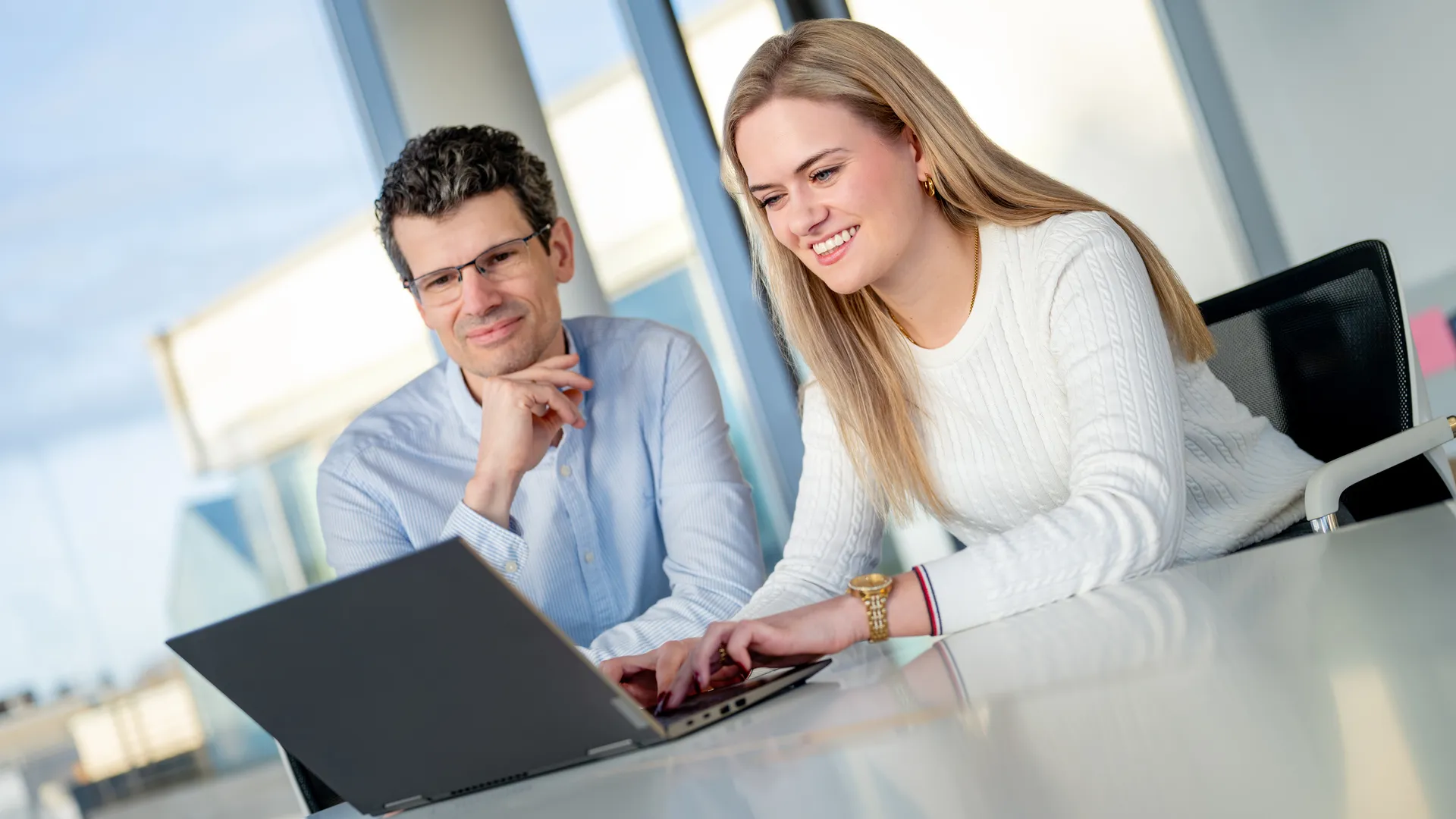 Ein Mann und eine Frau schauen auf einen Laptop