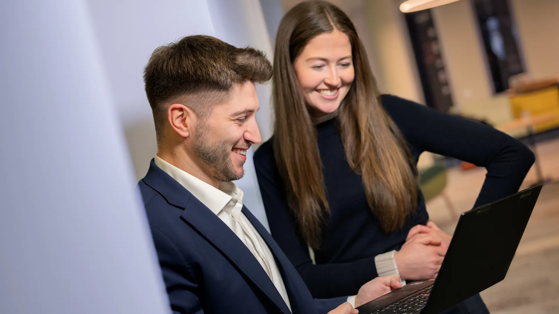 a man and woman looking at a laptop