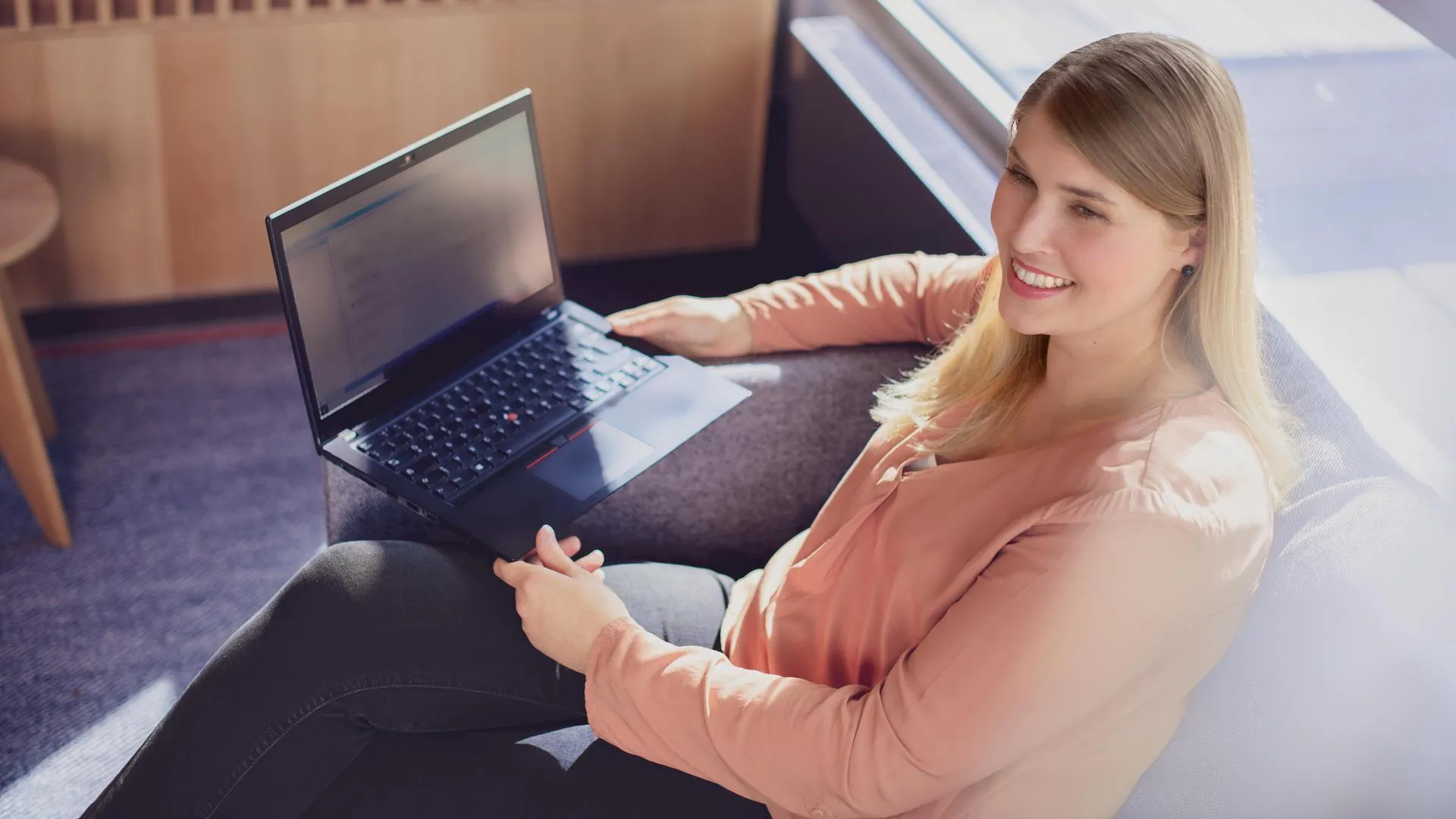 Eine Frau, die auf einer Couch sitzt und einen Laptop hält