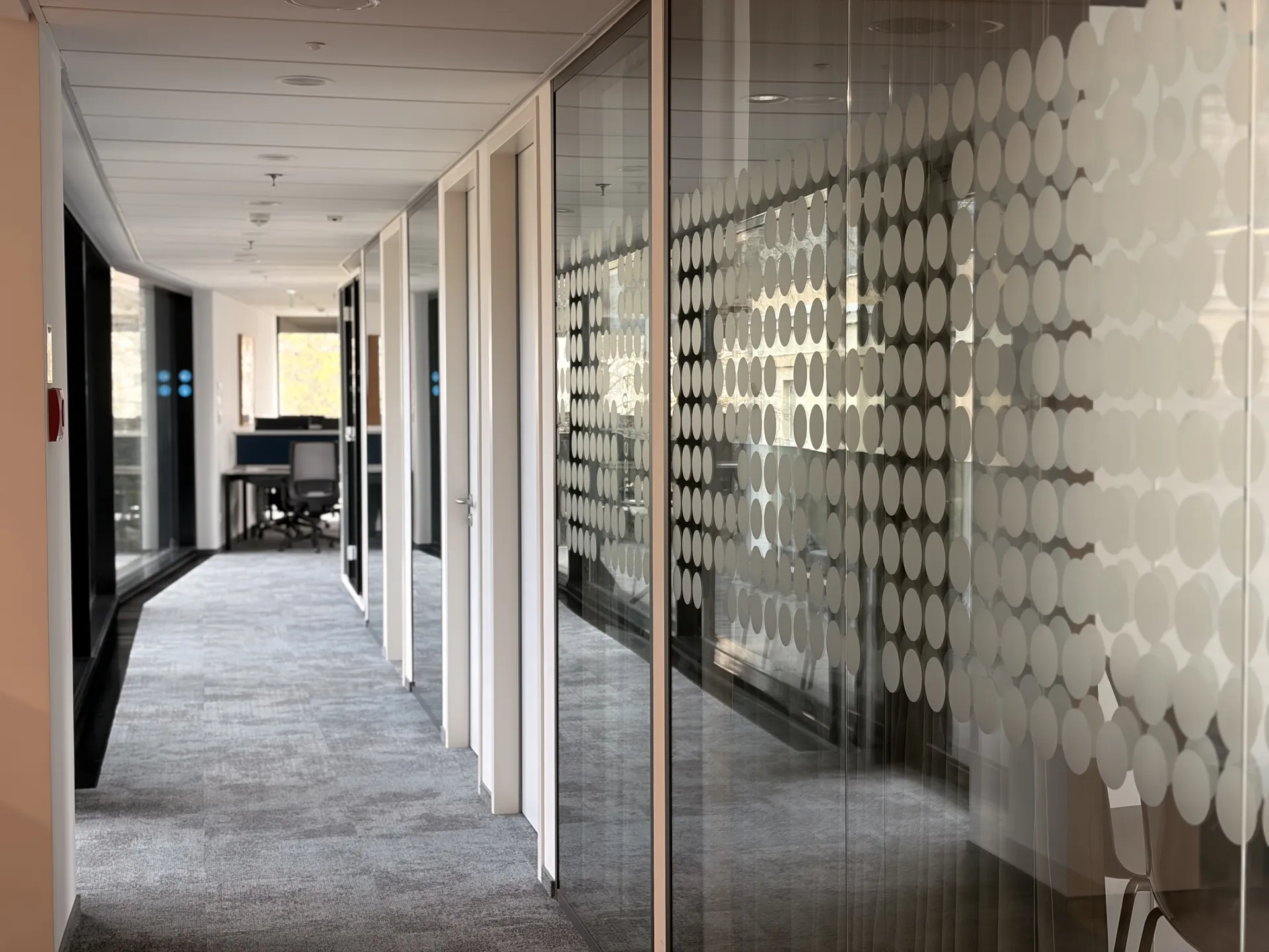 Moderner Büroflur mit Glaswänden und Punktmuster