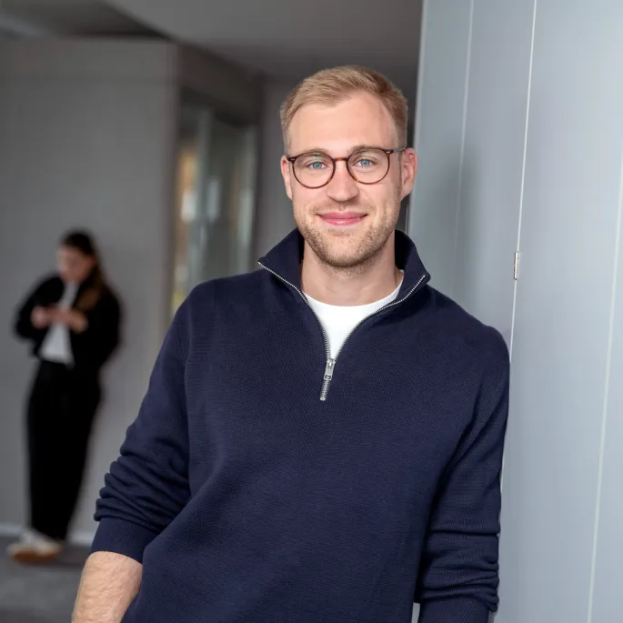 A young man leans against the wall and smiles. 