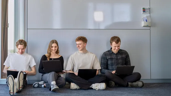 a group of people sitting on the floor with laptops