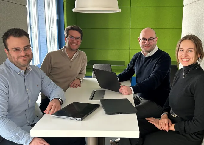 Eine Gruppe von Leuten, die an einem Tisch mit Laptops sitzen