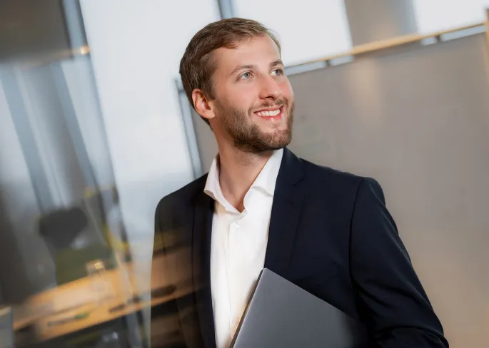 Ein Mitarbeiter von zeb hält einen Laptop unter dem Arm