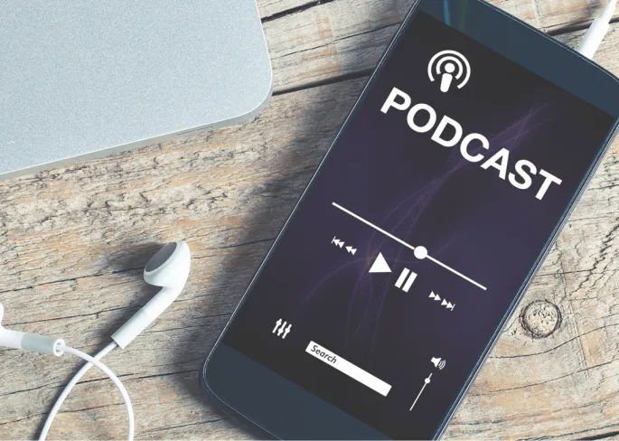 A smartphone with plugged in headphones, on which a podcast is playing