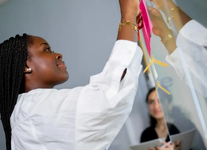 a woman writing on a glass board