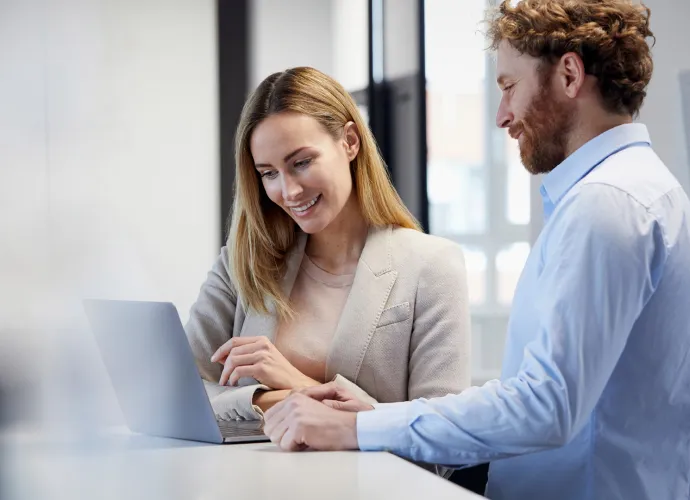 A woman and a man are looking at a laptop