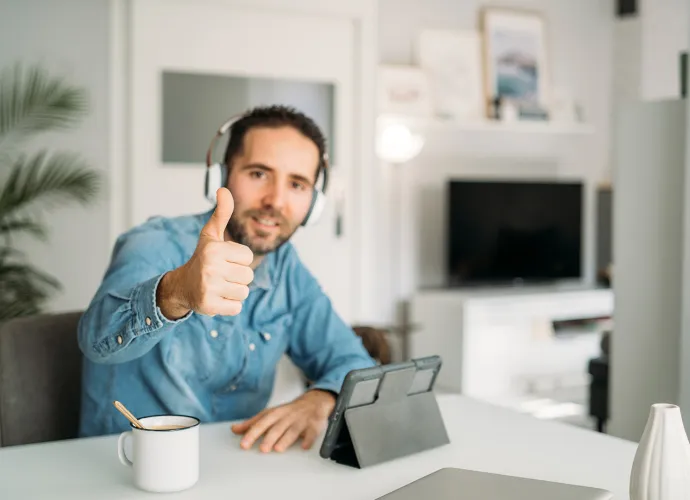 A man wearing headphones giving a thumbs up