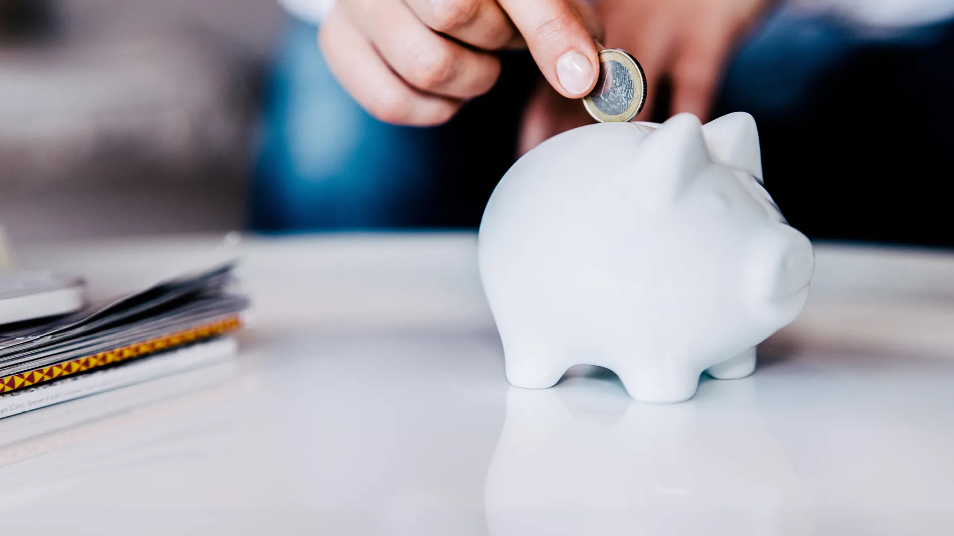 a person putting a coin into a white piggy bank