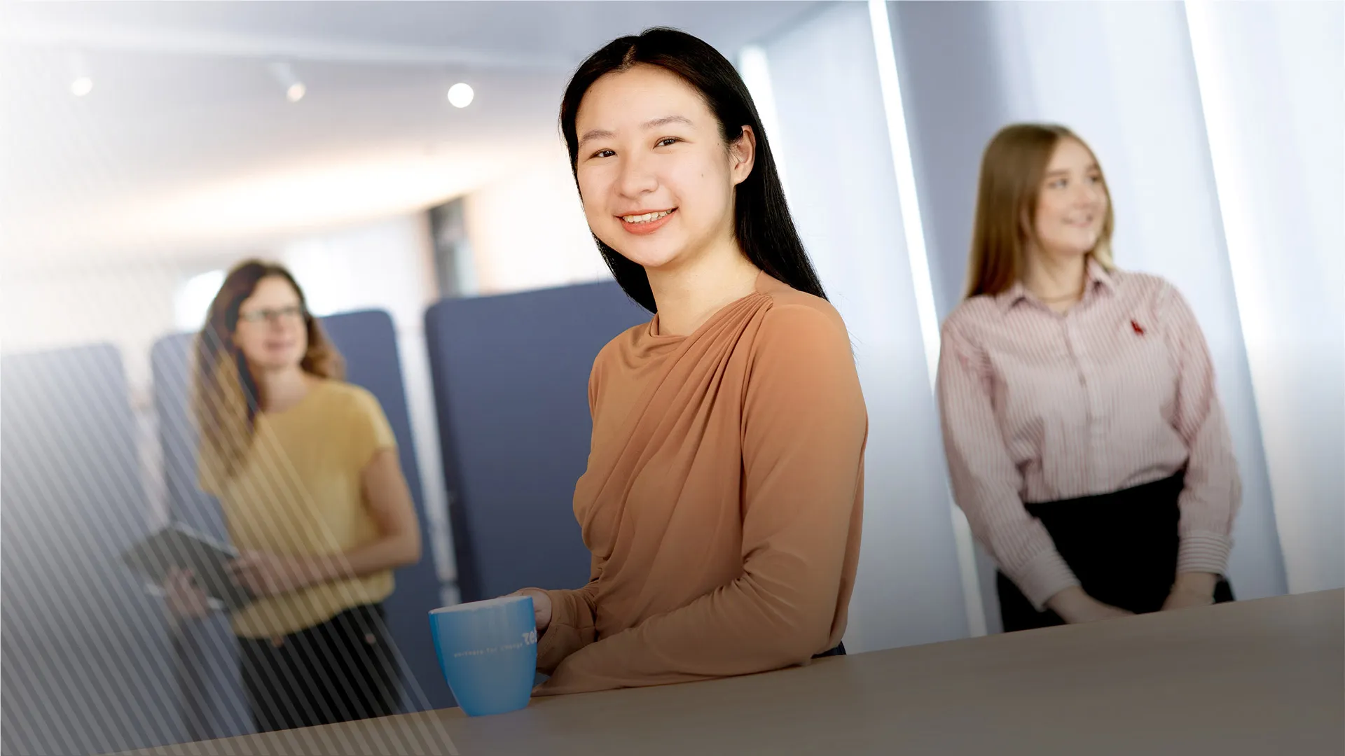 Three women are looking in different directions. One of them is holding a tablet in her hands.