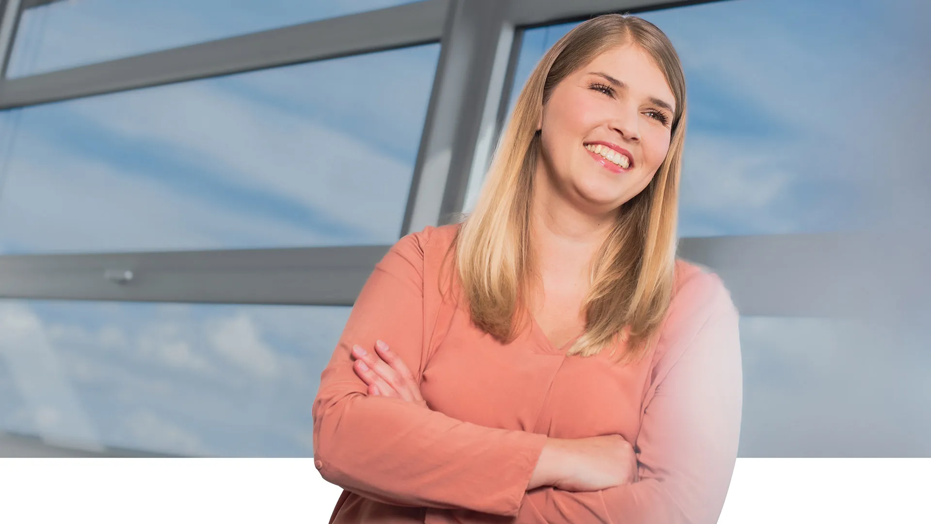 A woman crosses her arms and smiles to the right.