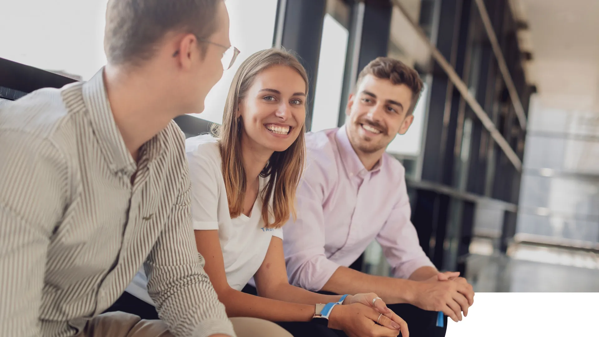 Three students are sitting together. One student smiles into the camera.