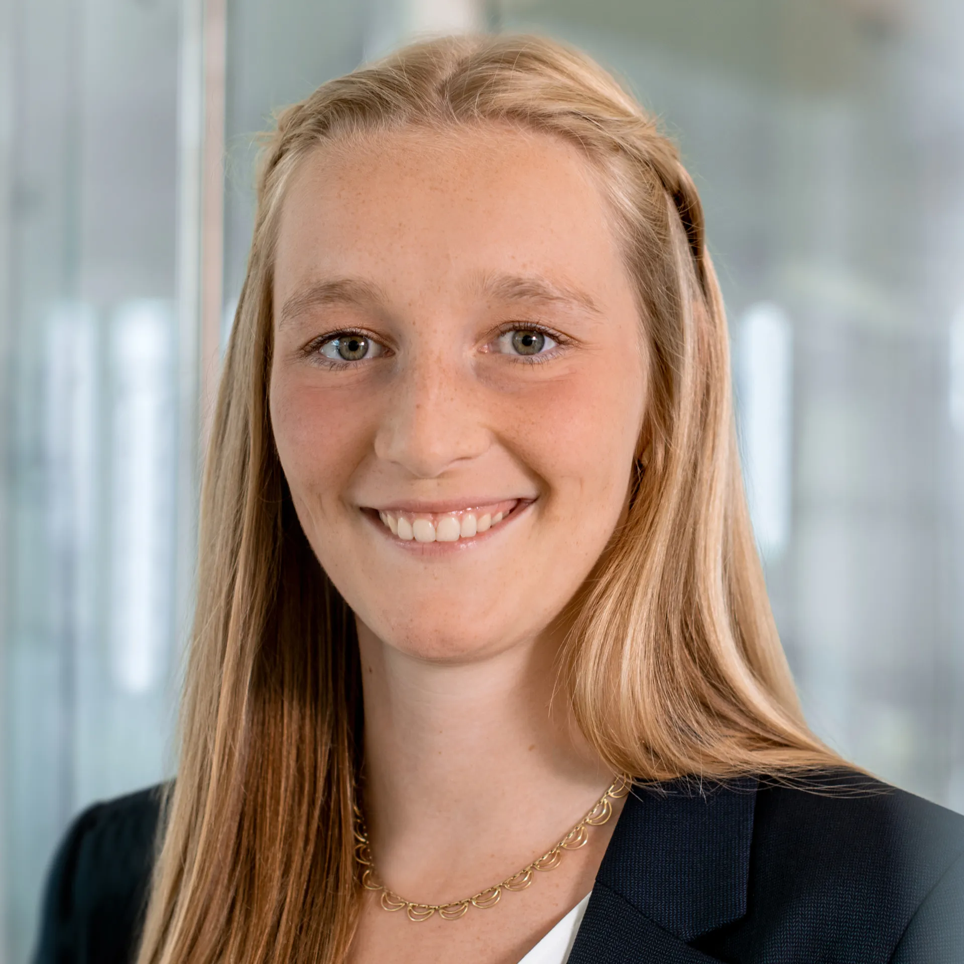 A woman wearing a blazer is smiling at a camera.