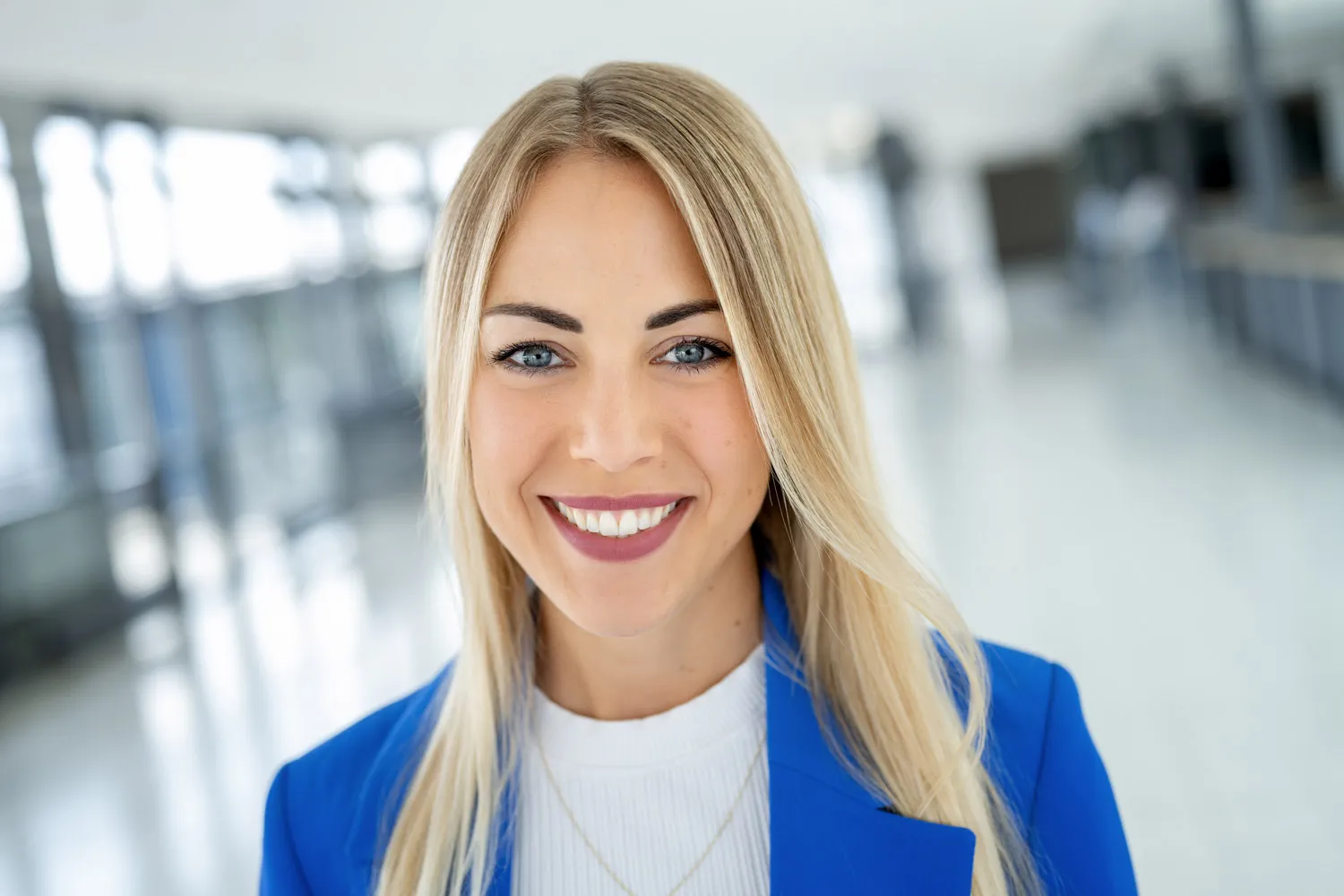 A woman wearing a blazer smiles into the camera