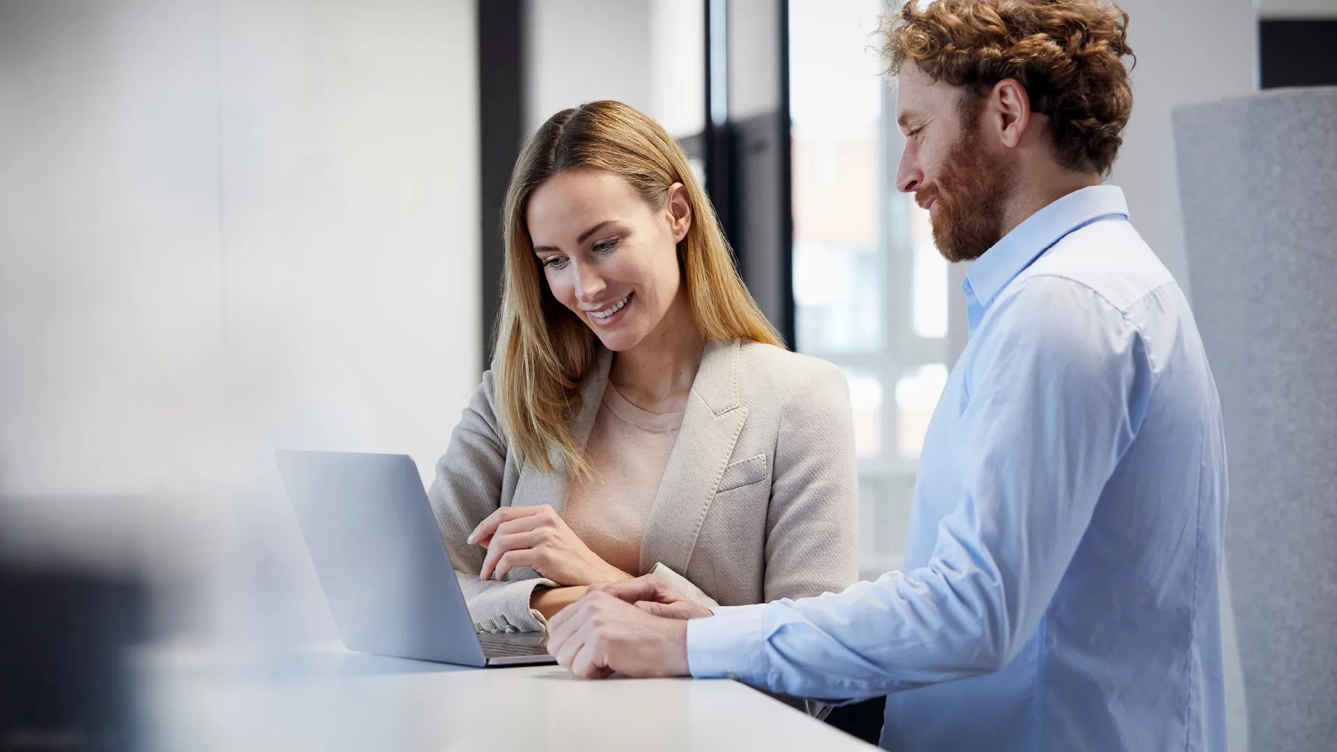 A woman and a man are looking at a laptop