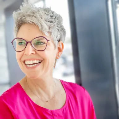 A woman wearing glasses is smiling.